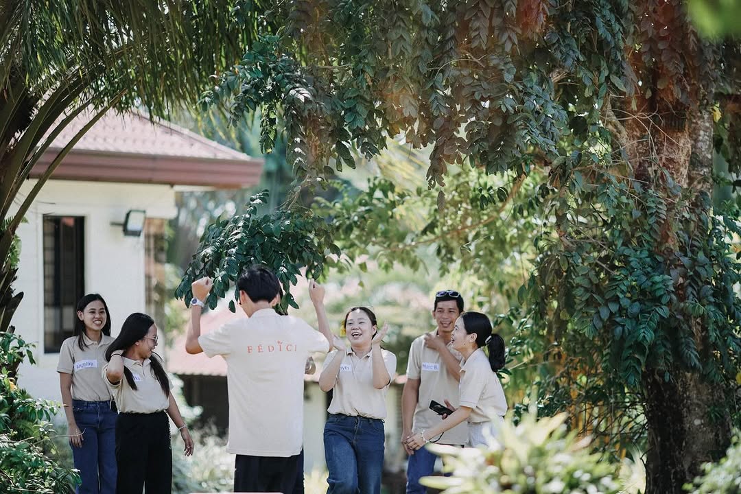 Fédici team in branded tan uniforms walking in garden setting